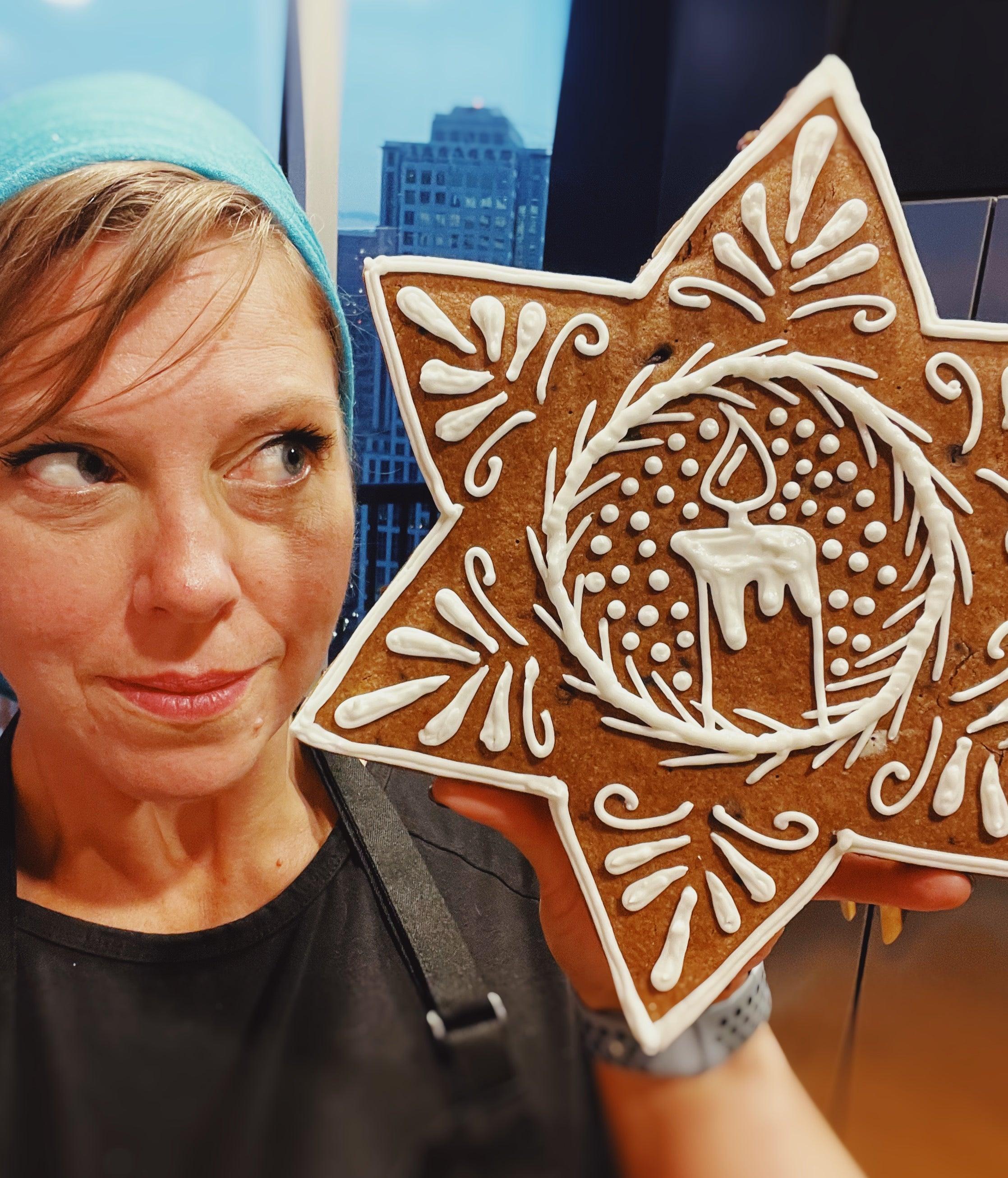 Baker holding star of david lebkuchen cookie with icing designs