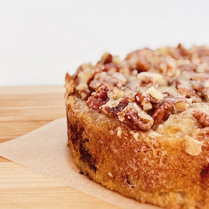 Buttermilk cake with pecans on top sitting on parchment paper